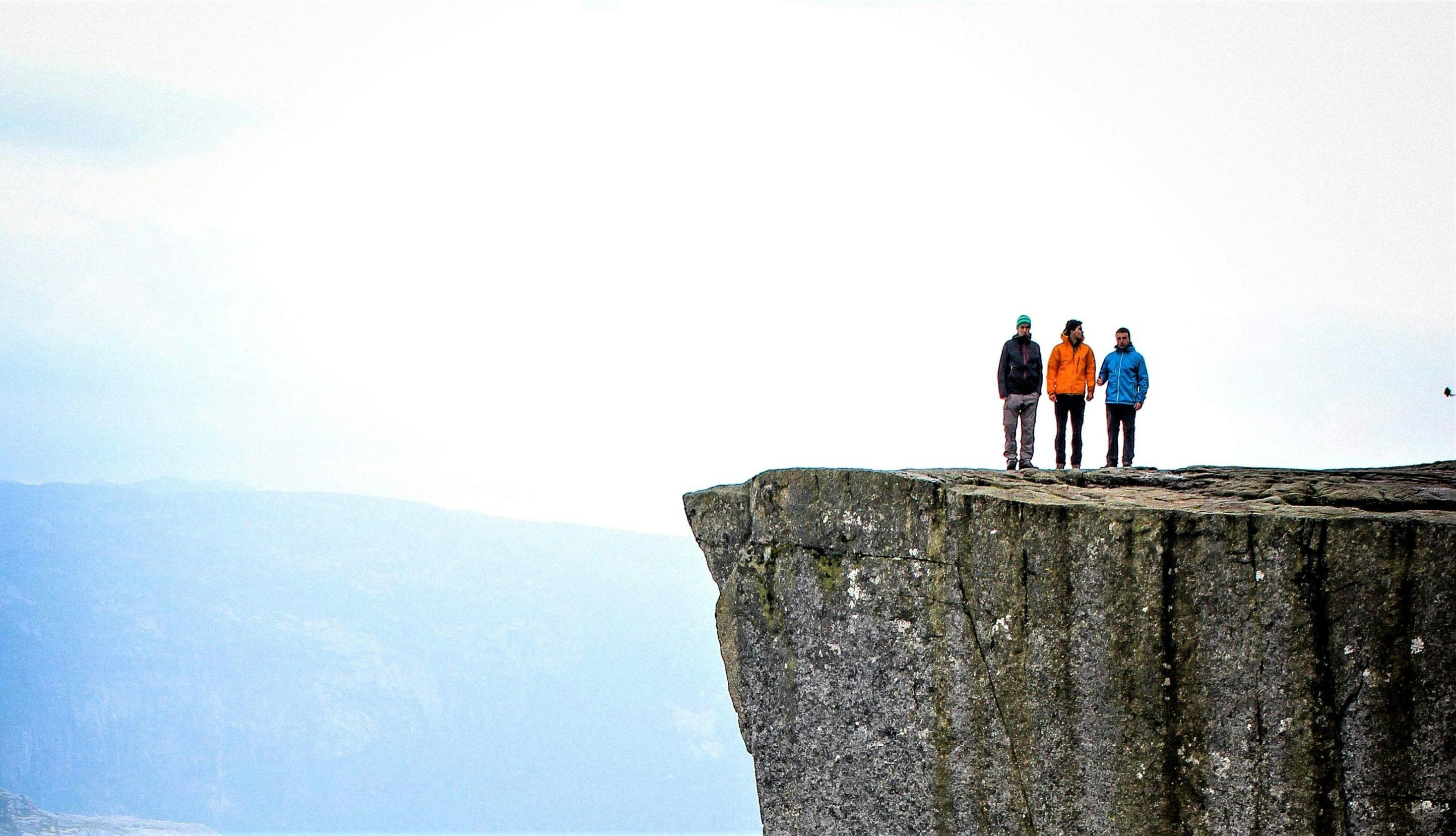 Tre personer som står på en fjellhylle. 
