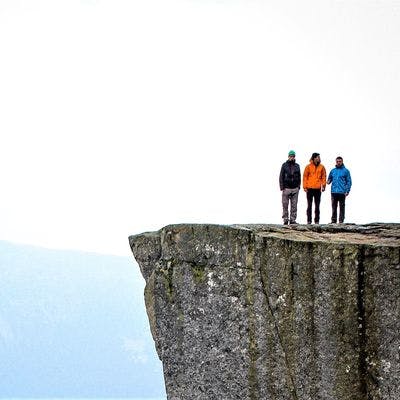 Tre personer som står på en fjellhylle. 
