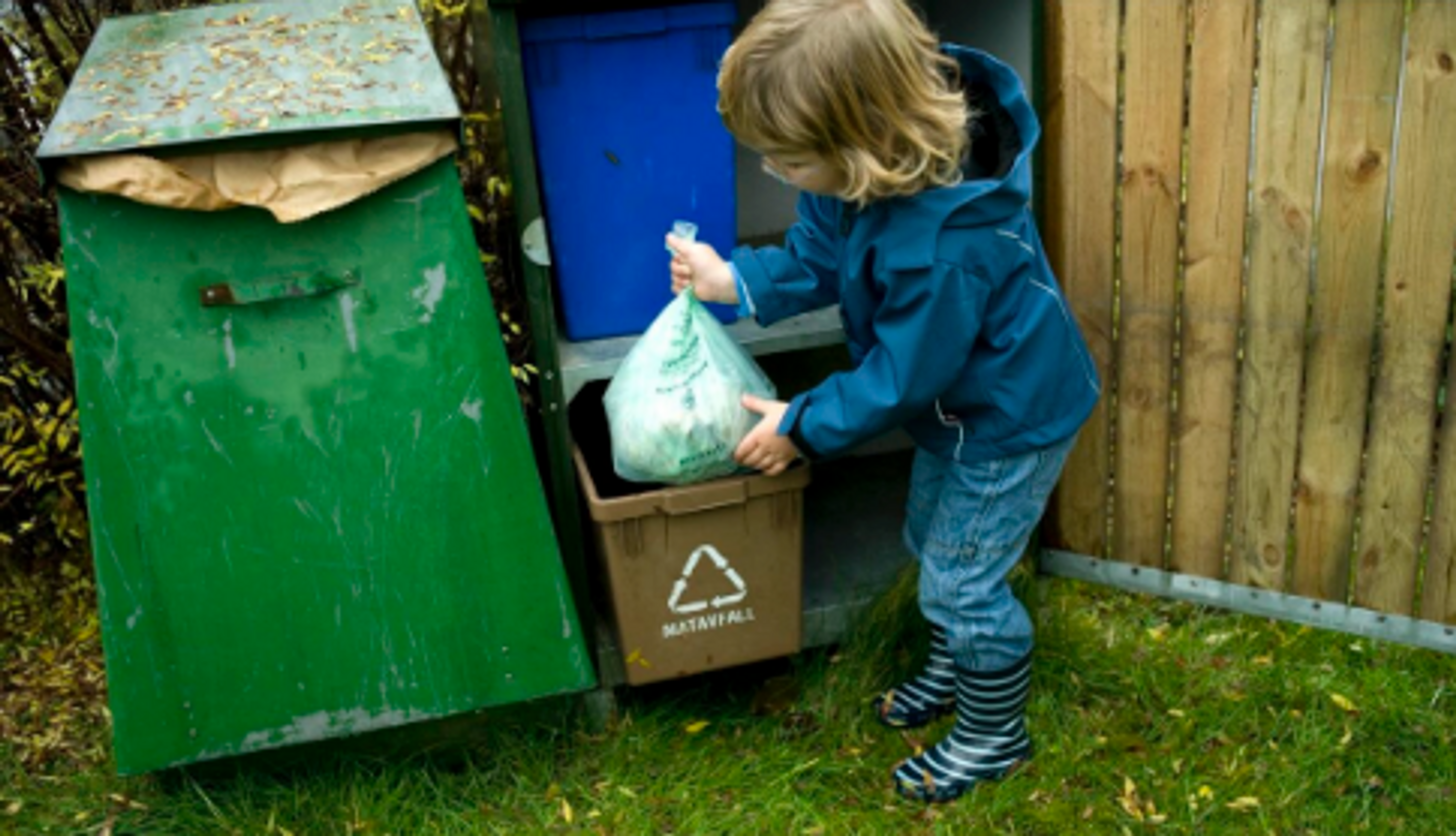 Barn som putter matavfall i søppeldunk.