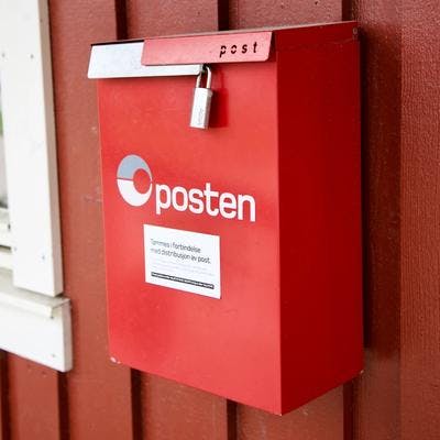 Rød postkasse på rød vegg. 