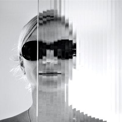 Kvinne med solbriller bak glassvegg.