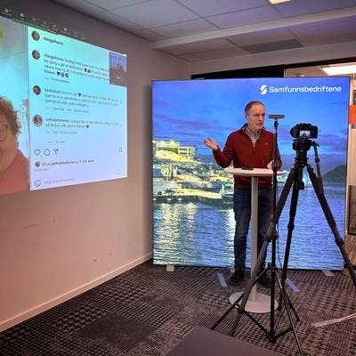 Mann som holder foredrag foran kamera, med presentasjon i bakgrunnen.