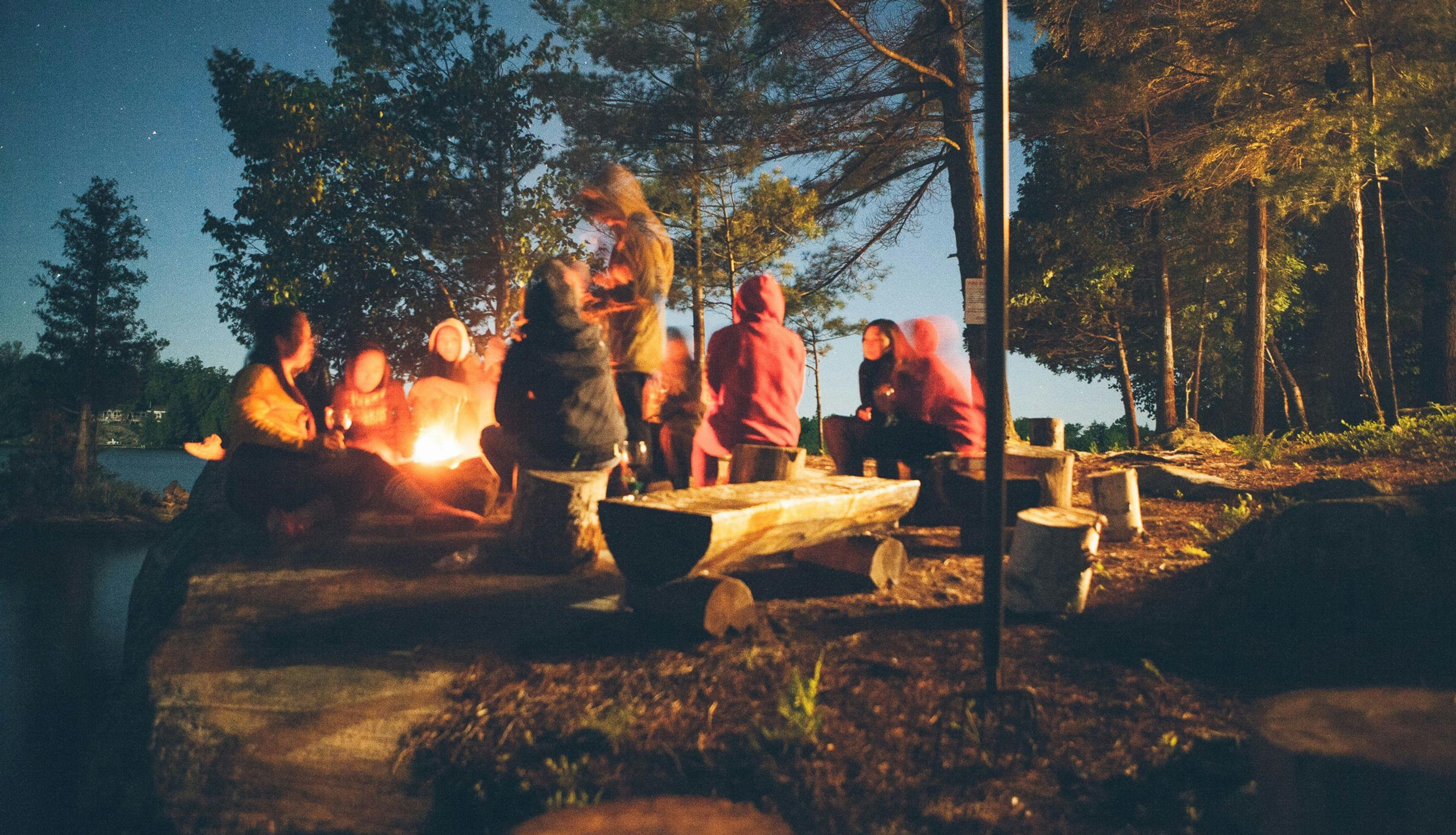 Personer som sitter ved leirbål om kvelden.