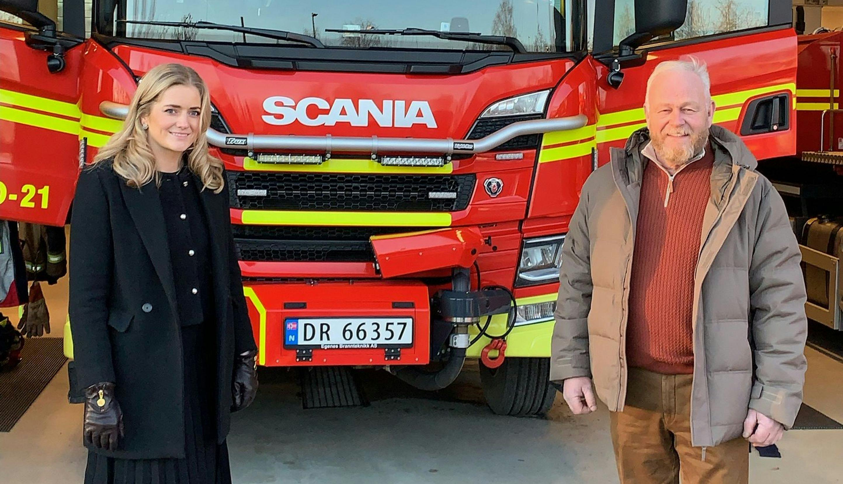 Emilie Enger Mehl og Harald Sunde foran brannbil i garasje. 
