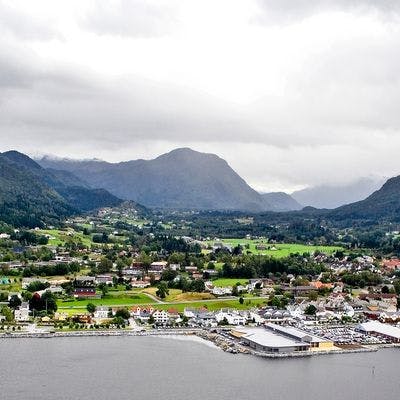 Oversiktsbilde av Eid kommune med fjord i forgrunn og fjell i bakgrunn.