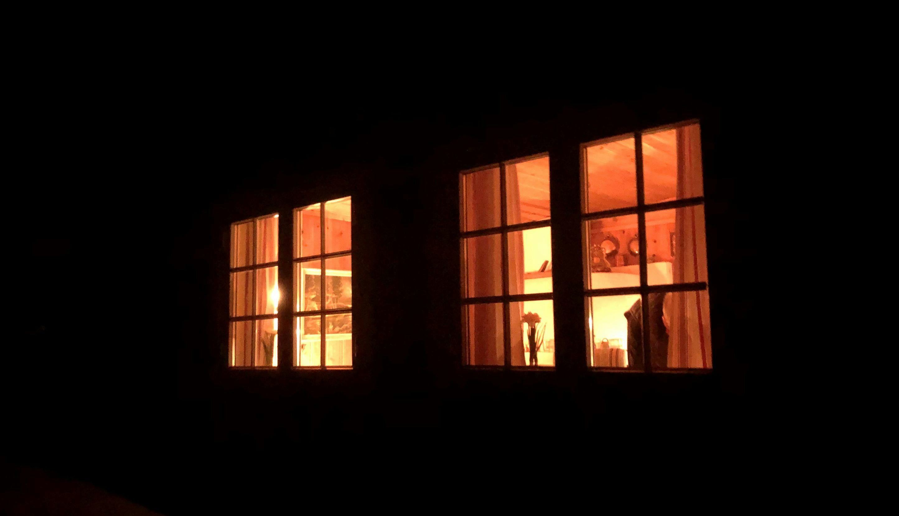 Lys fra hyttevinduer i mørket.