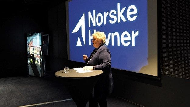 Erna Solberg holder foredrag med Norske Havner-logo i bakgrunnen.