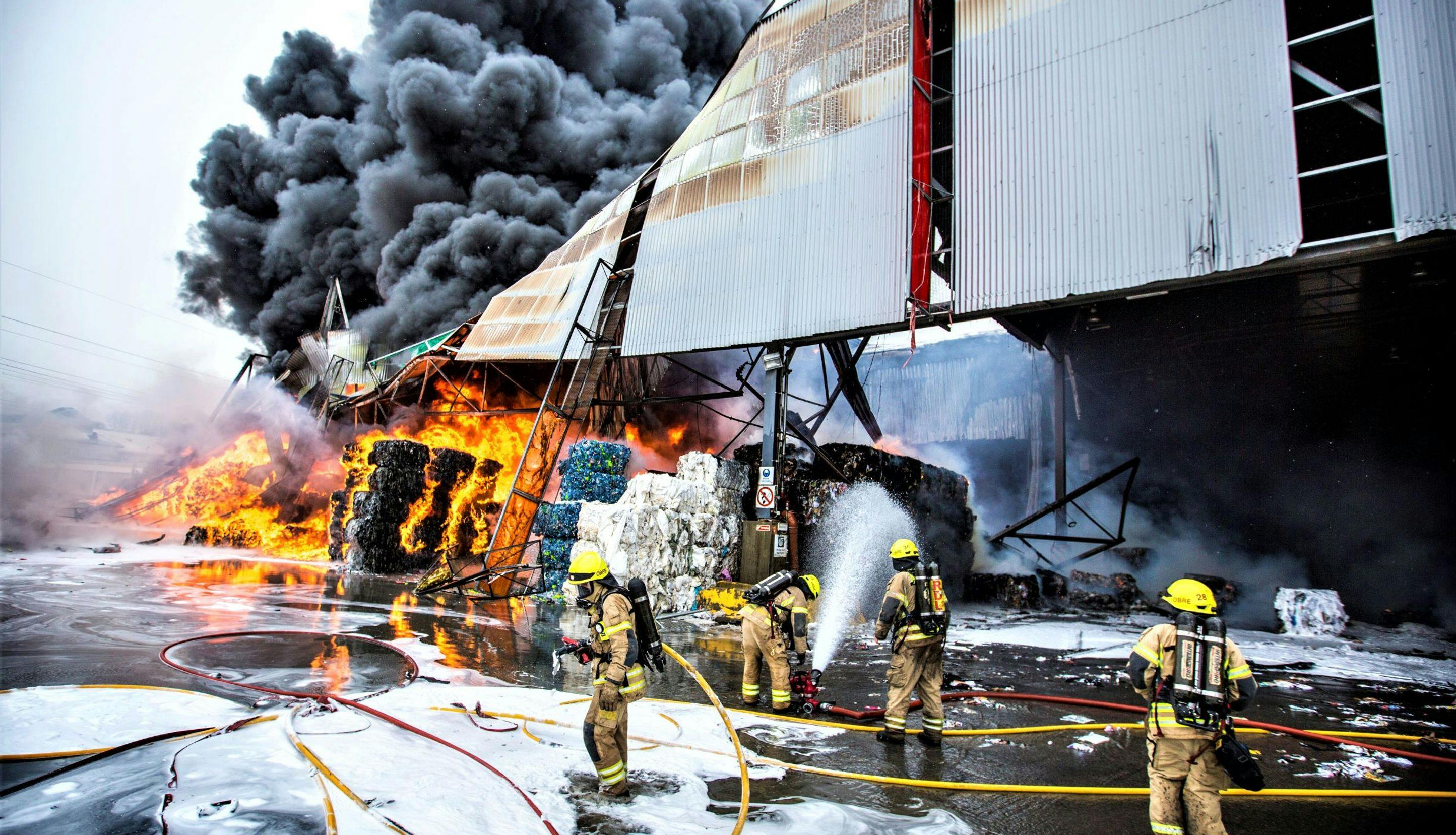 Brannkonstabler som slukker brann i gjenvinningsanlegg.