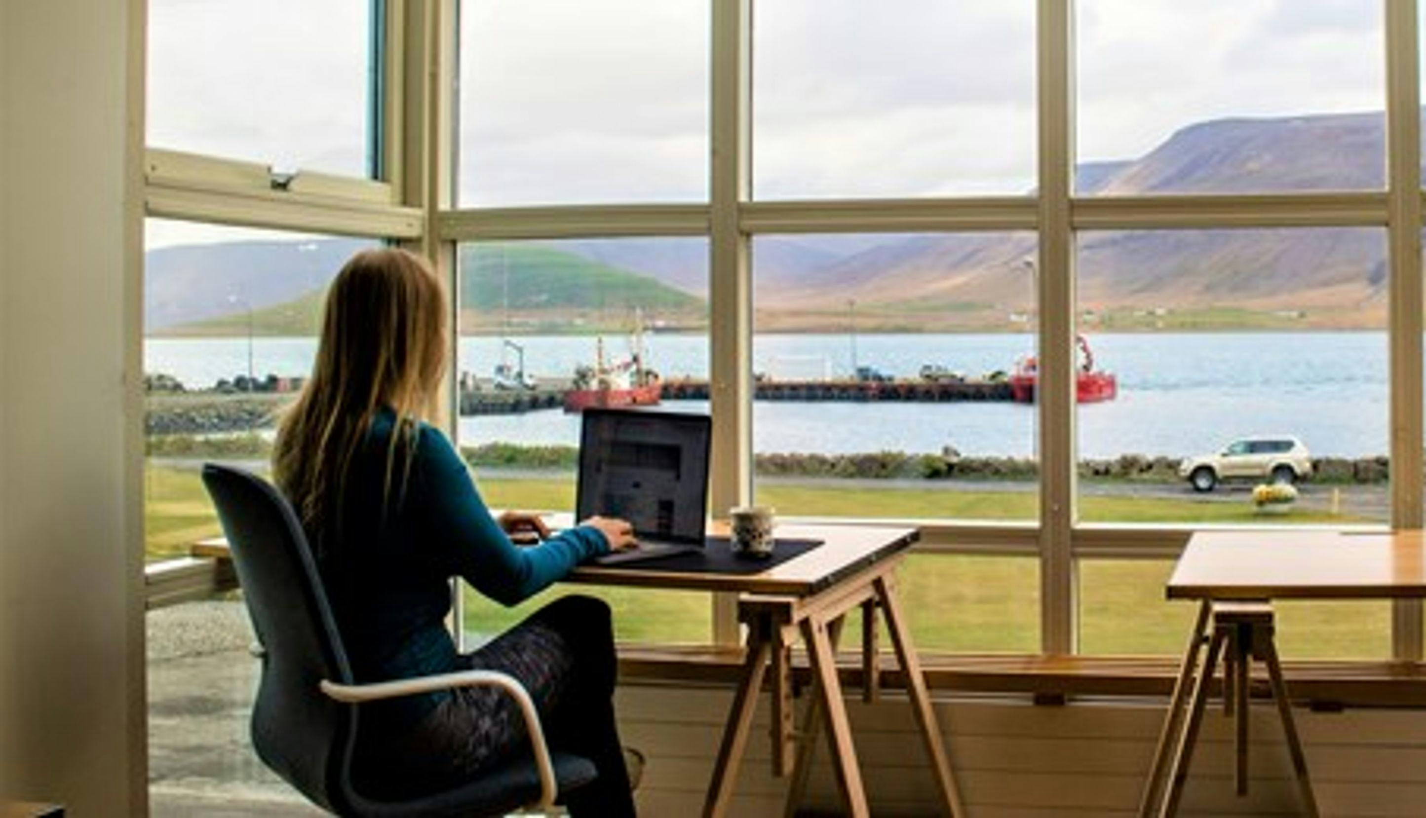 Kvinne som sitter på hjemmekontor med fin utsikt mot fjord.